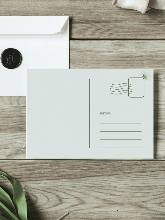 Eine Postkarte mit der Rückseite nach oben liegt auf einem Holztisch.  Achtsame Geschenke für Frauen. Alles auf Anfang